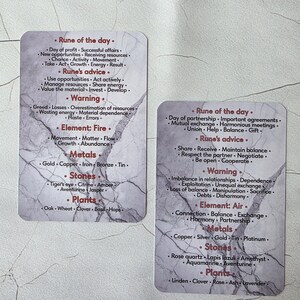 May include: Two tarot cards with a marble-like background. The cards feature lists of words under headings like "Rune of the day," "Rune's advice," and "Warning." The cards also list elements, metals, stones, and plants.