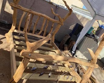 Puede incluir: Una rústica estructura de cama de madera con cabecero y piecero hechos de ramas naturales. El cabecero presenta un diseño único con soportes verticales y hojas decorativas de metal. La estructura de la cama es de madera marrón claro.