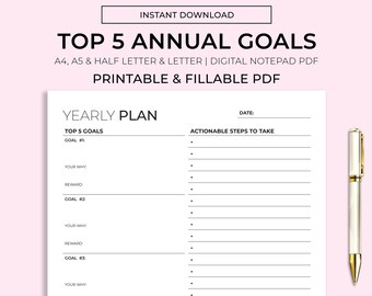 May include: A printable and fillable PDF yearly plan notepad with the text "Top 5 Annual Goals". The notepad includes sections for goals, reasons, rewards, and actionable steps. A gold and white pen is placed on the right side of the notepad.