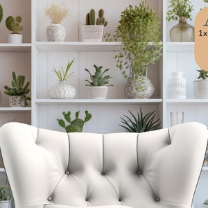 May include: A white armchair with button tufting sits in front of a white bookshelf filled with potted plants. The bookshelf has three shelves and is against a white wall. The text "1x Zoom Background" is visible on the right side of the image.