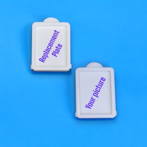 May include: Two white rectangular frames with rounded corners. The top frame says "Replacement Plate" in purple text. The bottom frame says "Your picture" in purple text.