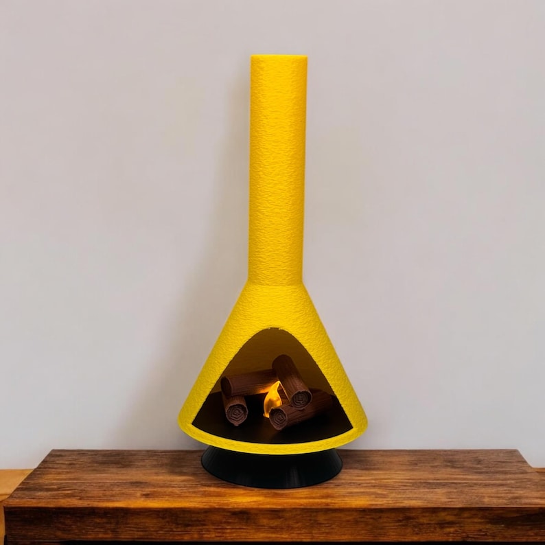 May include: A yellow ceramic fireplace with a black base and a faux fire inside. The fireplace is on a wooden surface.