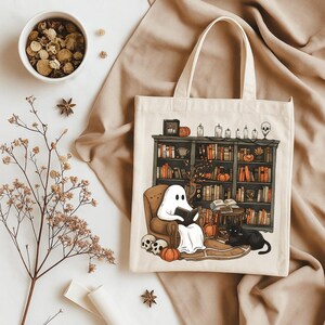 Op de afbeelding: Een witte tote bag met een zwart-witte illustratie van een geest die een boek leest in een bibliotheek. De bibliotheek heeft een donkerhouten boekenkast vol boeken en een zwarte kat die op de grond zit. De tote bag heeft een cr&egrave;mekleurige achtergrond en de illustratie bevindt zich in het midden van de tas.