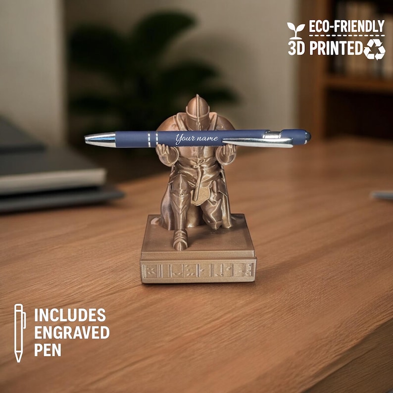 Bronze knight pen holder 3D printed in eco-friendly material, kneeling on a modern wooden desk while holding a custom engraved blue pen that reads "Your name." Office decor background includes a blurred laptop, books, and indoor plant. Overlay icons read “Includes Engraved Pen” and “Eco-Friendly 3D Printed,” highlighting the product's personalization and sustainability features for Etsy shoppers.