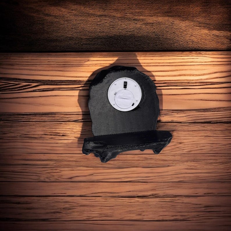 May include: A black 3D printed wall shelf shaped like a rock with a small round white clock face.