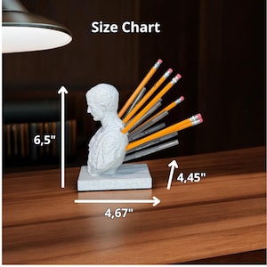May include: A white plaster bust of a man with pencils sticking out of his back. The bust is on a gray base and measures 6.5 inches tall, 4.67 inches wide, and 4.45 inches deep. Size Chart.