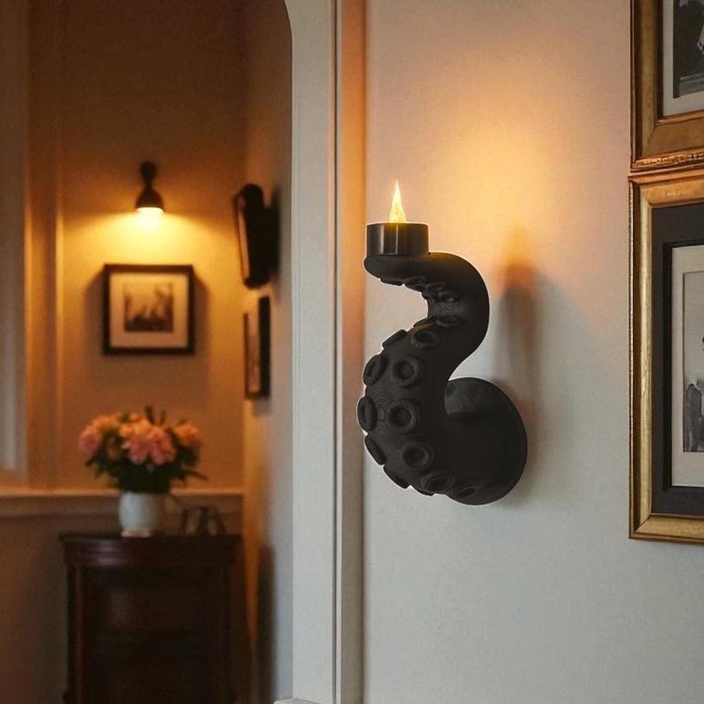 Wall-mounted octopus tentacle candle holder with LED tea light glowing warmly, adding spooky nautical charm to a cozy home interior. The kraken-inspired wall sconce blends gothic and fantasy style, perfect for Halloween décor, haunted houses, pirate-themed rooms, or unique gothic home accents. Handmade 3D printed tentacle wall art that creates eerie ocean vibes while providing a safe candlelight effect for alternative and witchy interiors.