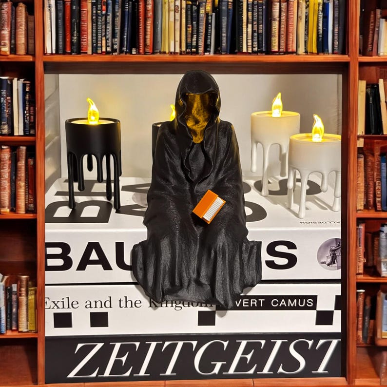 May include: A black hooded figure sits on a stack of books with the title "ZEITGEIST" on the bottom book. The figure is holding a small orange book. Three candles with dripping wax are on the shelf behind the figure.