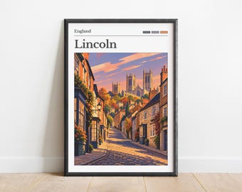 May include: A framed wall art print featuring a street scene in Lincoln, England. The illustration shows a cobblestone street leading toward a cathedral under a sunset sky. The text reads England and Lincoln, with three small color swatches.