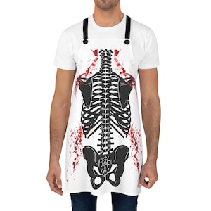May include: White apron with a black skeleton print and red blood splatter design. The skeleton is a full-body skeleton with a rib cage, spine, and pelvis.