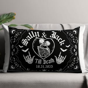 May include: Black rectangular pillow with a white design featuring skeletons kissing inside a heart, the names "Sally & Jack", bats, and the phrase "Till Death 10.31.2025". The pillow is on a gray couch.