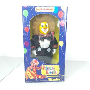 New in box, vintage porcelain Simba Toys Clown, yellow face statue, very nice lace clothing, checkered accents and bow, Clown world