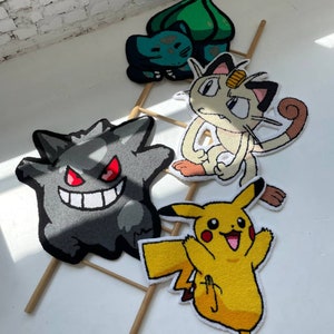 May include: Four colorful, cartoon character rugs. A gray Gengar rug with red eyes and a wide smile. A yellow Pikachu rug with arms raised. A Meowth rug with a gold coin on its head. A green and blue Bulbasaur rug.