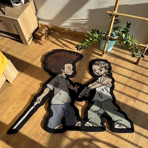 May include: A rug featuring two cartoon characters, one holding a sword and the other holding a gun. The characters are drawn in a black and white style with some grey shading. The rug is made of a soft, plush material.