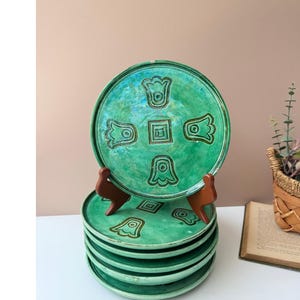 May include: A set of three ceramic mugs with a speckled, matte finish. The mugs are in shades of cream, light gray, and dark gray. Each mug has a simple, minimalist design and a rounded handle. The mugs are stacked on top of each other.