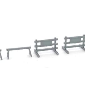 May include: A set of five miniature gray plastic construction barriers and sawhorses. The collection includes three simple A-frame sawhorses and two taller barricades featuring horizontal crossbars and a central rectangular sign panel.