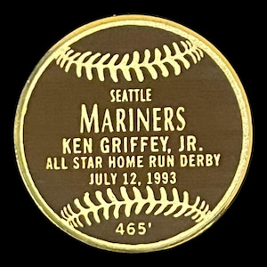 May include: A circular, bronze-colored commemorative coin with gold trim. The coin features the text "SEATTLE MARINERS KEN GRIFFEY, JR. ALL STAR HOME RUN DERBY JULY 12, 1993" and the distance "465'" in white lettering. Baseball stitching design surrounds the text.