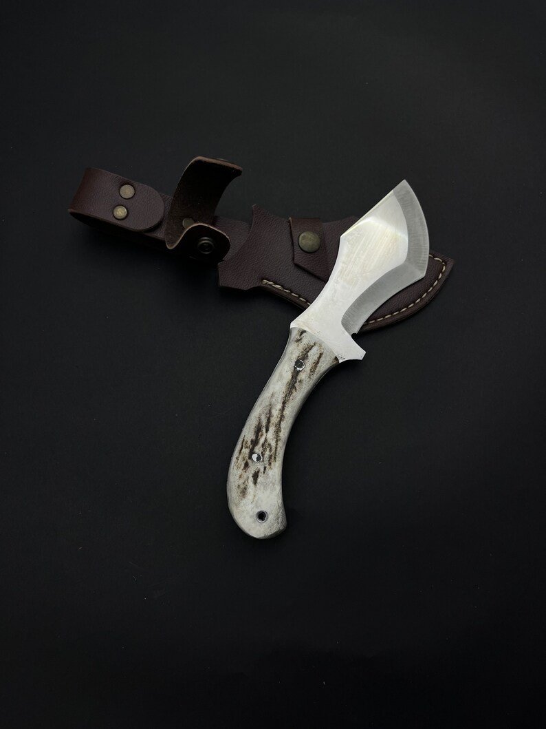 May include: A white-handled knife with a brown leather sheath. The knife has a curved blade and a white handle with a dark brown pattern.