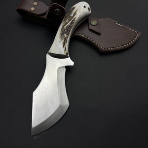 May include: A silver knife with a brown and white stag horn handle and a leather sheath.