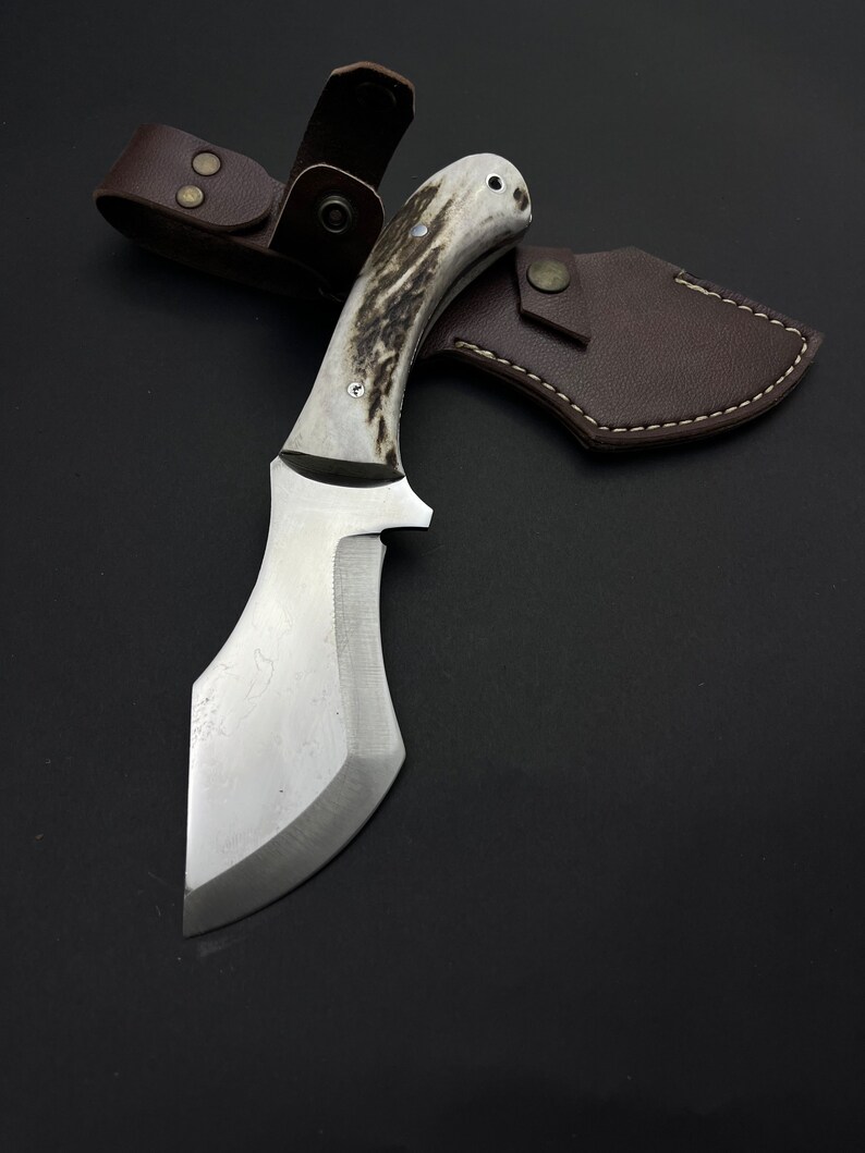 May include: A silver knife with a brown and white stag horn handle and a leather sheath.