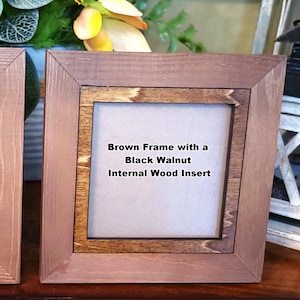 May include: Two square wooden frames with brown exteriors. One has an ebony internal wood insert, the other a black walnut insert. Text on the frames reads: "Brown Frame with an Ebony Internal Wood Insert" and "Brown Frame with a Black Walnut Internal Wood Insert."