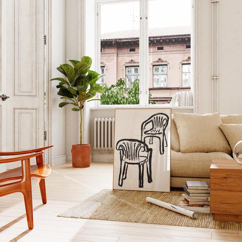 May include: An interior scene featuring a framed art print with two black line-drawn chairs. A large potted plant and a wooden chair are in the foreground. A beige sofa, wooden coffee table, and a window with a view of a building are also visible.