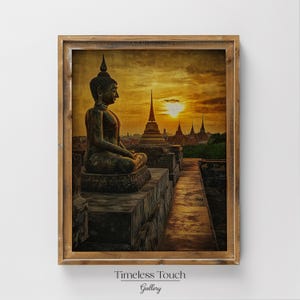 May include: Framed print of a seated Buddha statue overlooking a temple complex at sunset. The artwork features warm tones of gold, orange, and brown, with the text "Timeless Touch Gallery" at the bottom.