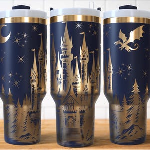Puede incluir: Vaso t&eacute;rmico azul marino con un dise&ntilde;o de castillo dorado, estrellas y una luna creciente. El vaso tiene una tapa blanca, ribete dorado y un asa azul oscuro. El dise&ntilde;o incluye un drag&oacute;n y elementos forestales.