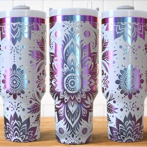 May include: Three white insulated tumblers with a floral mandala design in iridescent purple, blue, and pink. Each tumbler has a white handle and lid. The design features detailed flower and leaf patterns.