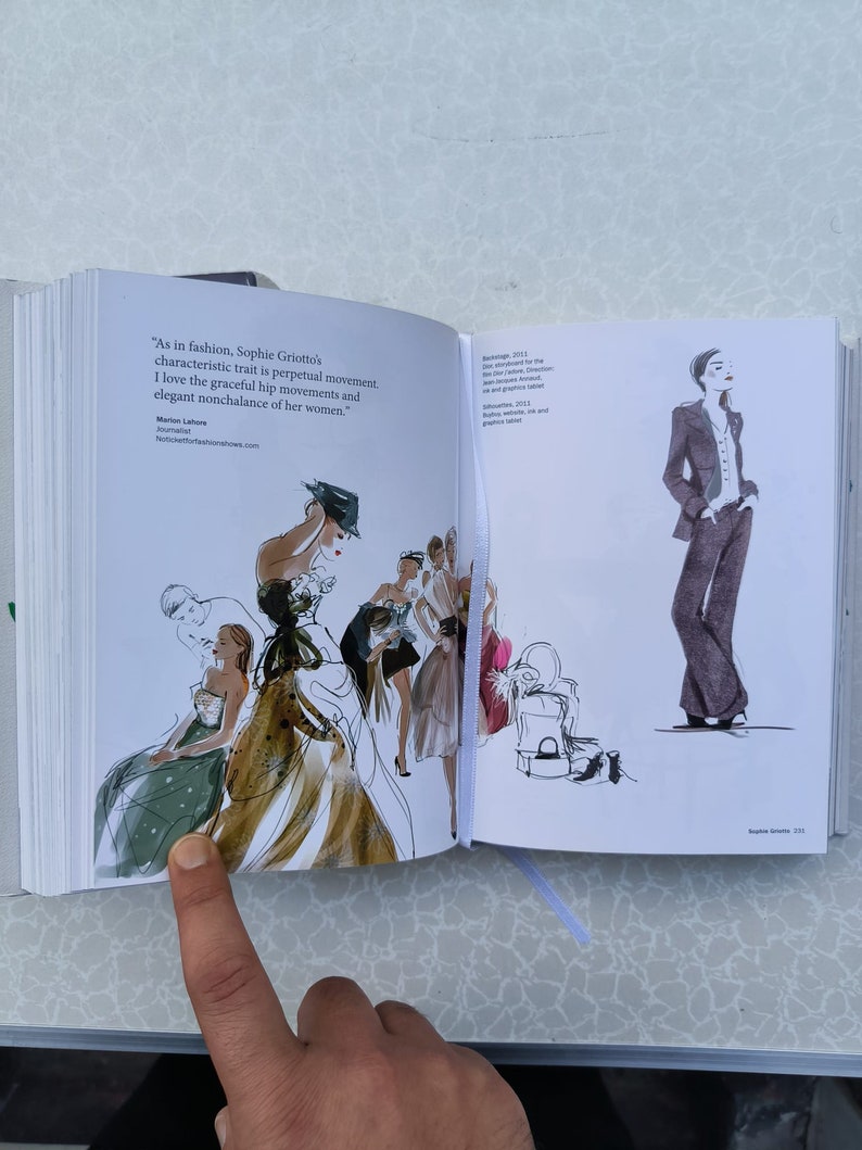 May include: An open book with a watercolour illustration of women in dresses and hats. The text on the page reads "As in fashion, Sophie Griotto's characteristic trait is perpetual movement. I love the graceful hip movements and elegant nonchalance of her women." Marlon Lahore 2011.