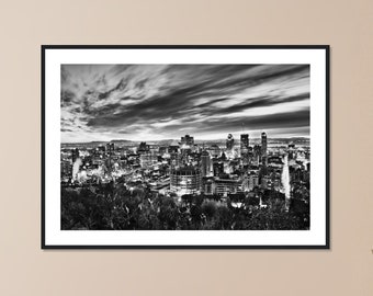 Puede incluir: Una fotografía en blanco y negro de un horizonte urbano con un cielo nublado. La ciudad está iluminada con luces y los edificios son altos y modernos.