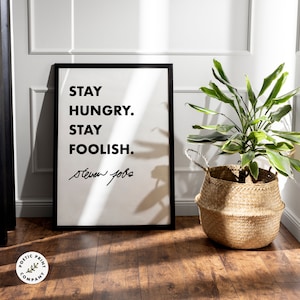 Peut inclure: Impression de citation motivationnelle en noir et blanc avec le texte "Stay Hungry. Stay Foolish." et la signature "Steve Jobs".