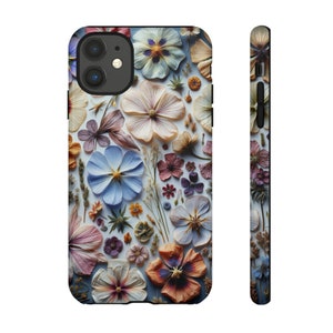 May include: A phone case with a floral design featuring pressed flowers in shades of blue, purple, pink, and yellow on a white background.