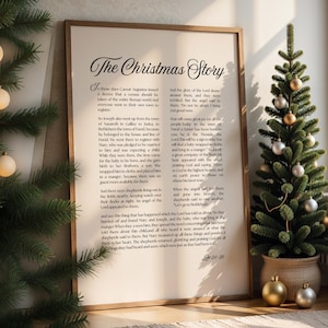 May include: A framed print of "The Christmas Story" text, with a Christmas tree and baubles in the background. The text is in a decorative font and includes Bible verses. The frame is a light brown colour.