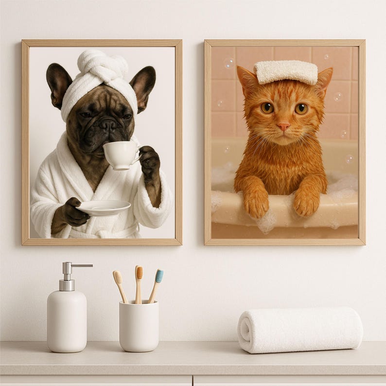 May include: Two framed prints: a French bulldog in a white robe and towel, holding a teacup, and an orange cat in a bathtub with a towel on its head. The prints are in light brown frames.