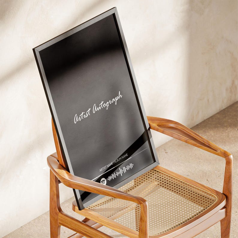 Puede incluir: Una impresi&oacute;n enmarcada en negro con las palabras "Artist Autograph" en escritura blanca. La impresi&oacute;n tambi&eacute;n incluye un c&oacute;digo de Spotify y el texto "ARTIST NAME ALBUM NAME". La impresi&oacute;n est&aacute; apoyada en una silla de madera con asiento tejido.