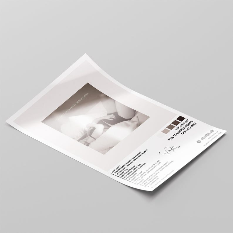 Puede incluir: Una impresi&oacute;n en papel blanco con una imagen en escala de grises y texto. El texto incluye "THE TORTURED POETS DEPARTMENT" y una lista de t&iacute;tulos de canciones. Hay una firma presente. La impresi&oacute;n est&aacute; en &aacute;ngulo sobre una superficie gris.