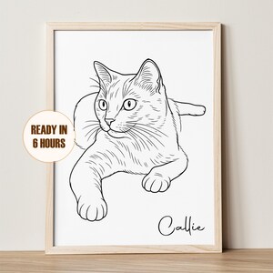 以下が含まれることがあります： キャリーという名前の猫の、額装された白黒の線画。猫は前足を伸ばして横たわっています。「READY IN 6 HOURS」というテキストが、左下の円形のバッジに表示されています。