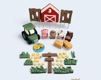 May include: A farm-themed cake topper set with a red barn, a green tractor, a pig, a sheep, a cow, a horse, two yellow chicks, a sign that says "Edwards Farm", and green grass and yellow flowers.
