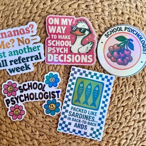 May include: A collection of colorful stickers with various designs and text. One sticker features a duck wearing sunglasses, another says "Bananas? Me? No - just another full referral week." Other stickers include "School Psychologist" and a sardine design.