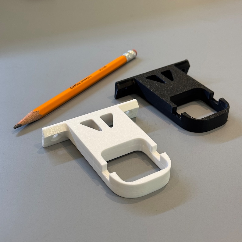 An image showing black and white extended mounting brackets for Govee Permanent Outdoor Lights 2 next to a pencil for scale