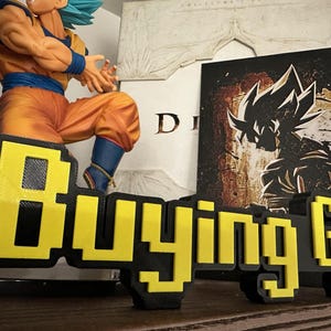 May include: A yellow and black 3D printed sign that reads "Buying GF".