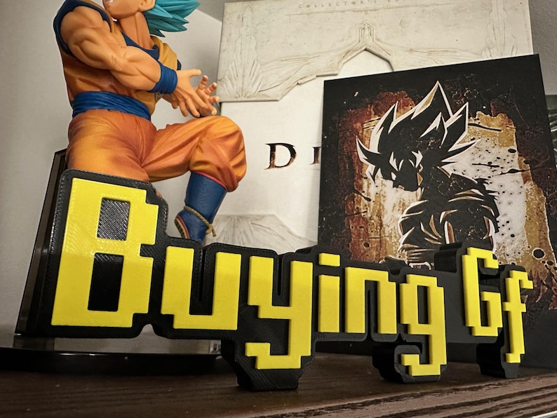 May include: A yellow and black 3D printed sign that reads "Buying GF".