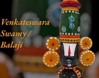 May include: A colorful wooden figurine of Venkateswara Swamy, also known as Balaji, a Hindu deity. The figurine is painted in shades of green, red, yellow, and black, with intricate details. The figurine is a traditional Indian art form.