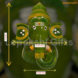 May include: Green wooden hand-painted Ganesha statue with yellow accents. The statue is 4 inches tall, 3 1/2 inches wide, and 2 3/4 inches deep.