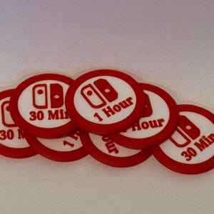 May include: A collection of red and white circular tokens. Each token features a game controller icon and text indicating time increments of "30 Min" and "1 Hour". The tokens are likely related to gaming.