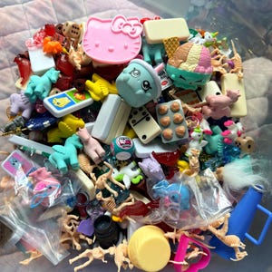 May include: A set of three ceramic mugs with a speckled, matte finish. Each mug features a different color: light blue, cream, and gray. The mugs have a simple, modern design with a rounded shape and a comfortable handle.