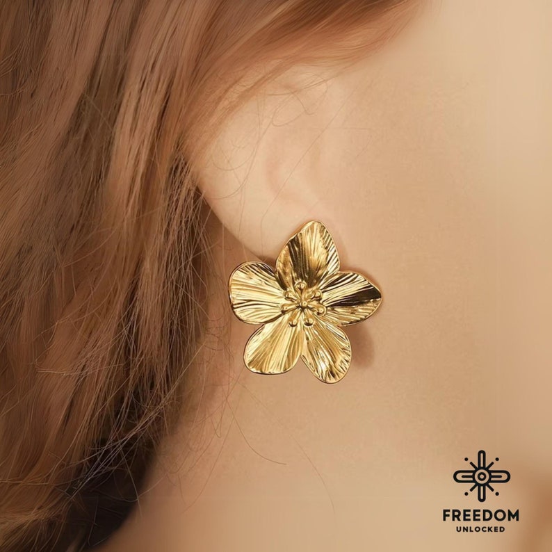 Op de afbeelding: Gouden oorbellen in de vorm van een bloem. De oorbellen zijn getextureerd en hebben een gedetailleerd ontwerp.