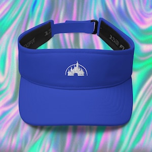 May include: A royal blue visor with a white embroidered image of a castle. The visor has a black adjustable strap with the text "One Size Fits Most" printed on it.