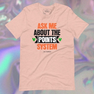 May include: A light peach-colored t-shirt with the text "ASK ME ABOUT THE POINTS SYSTEM" in orange and black. The shirt also includes two green Mickey Mouse head icons and the text "DVC MEMBER".